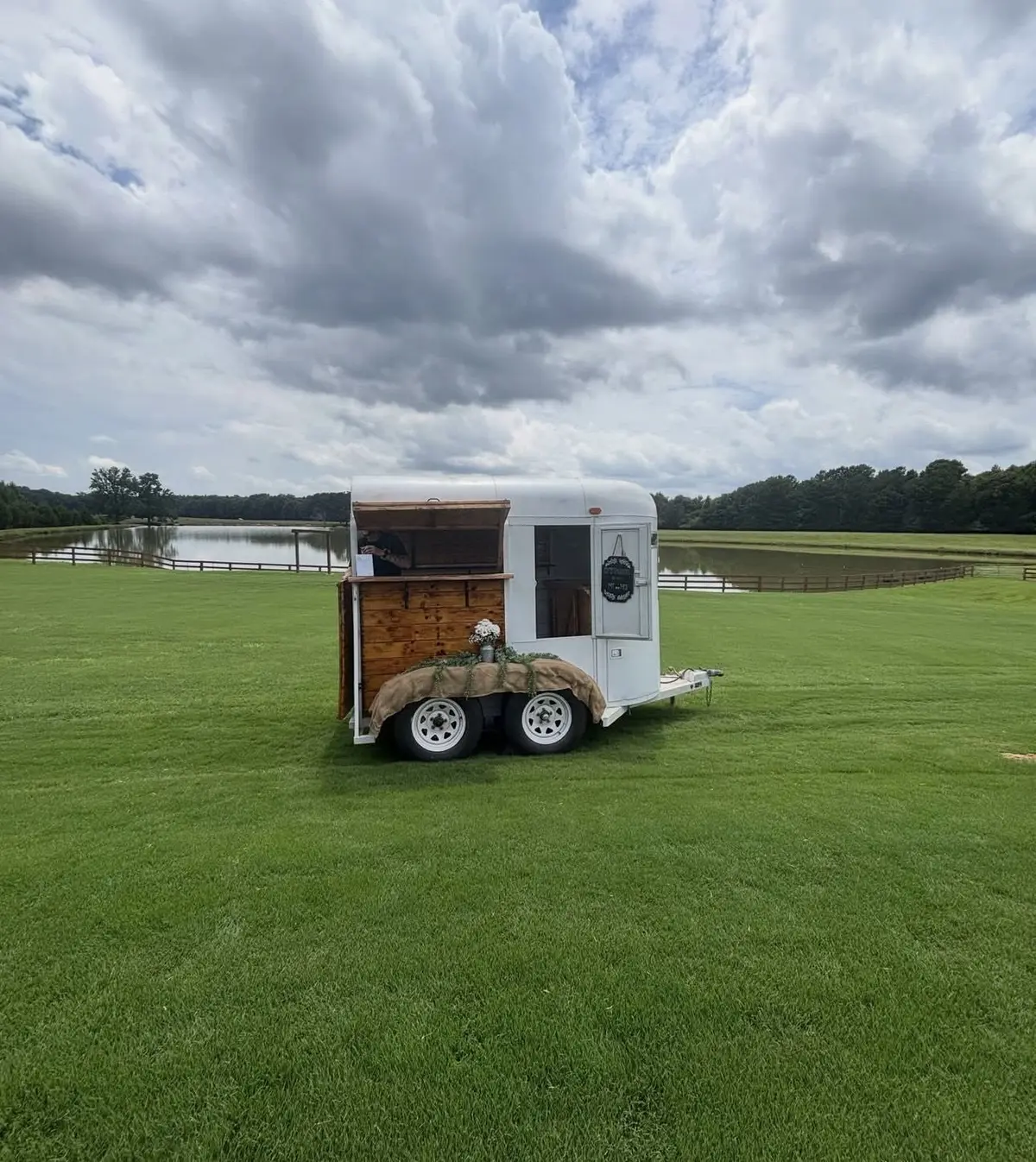 Clear Your Schedule horse-trailer mobile bar beside a pond at an outdoor venue